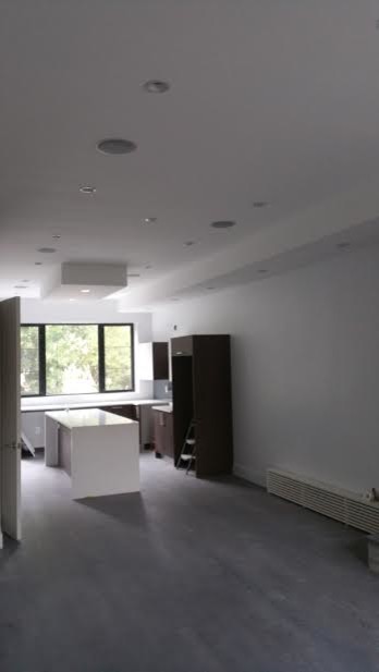 This is an example of a medium sized contemporary l-shaped open plan kitchen in New York with flat-panel cabinets, medium wood cabinets, quartz worktops, grey splashback, glass tiled splashback, stainless steel appliances, light hardwood flooring, an island and brown floors.