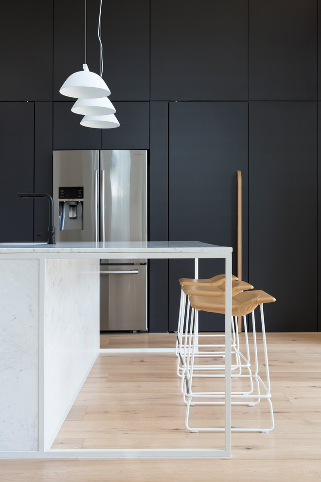 Ejemplo de cocina contemporánea con armarios con paneles lisos, electrodomésticos de acero inoxidable, suelo de madera clara, una isla, suelo beige y con blanco y negro