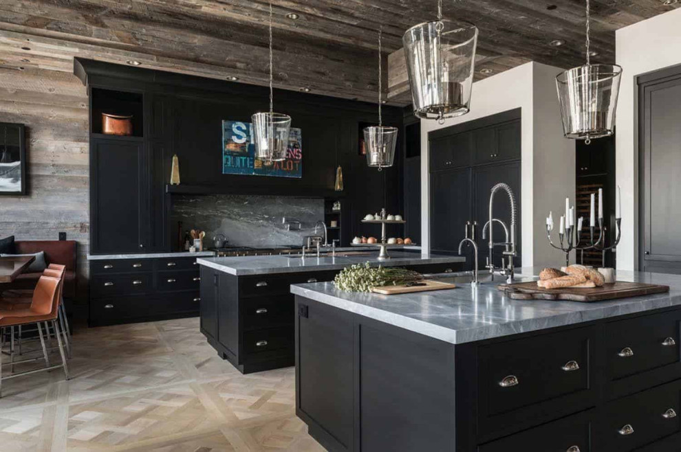 Photo of a rustic kitchen/diner in Denver with a submerged sink, black cabinets, grey splashback, stone slab splashback, light hardwood flooring, multiple islands and grey worktops.