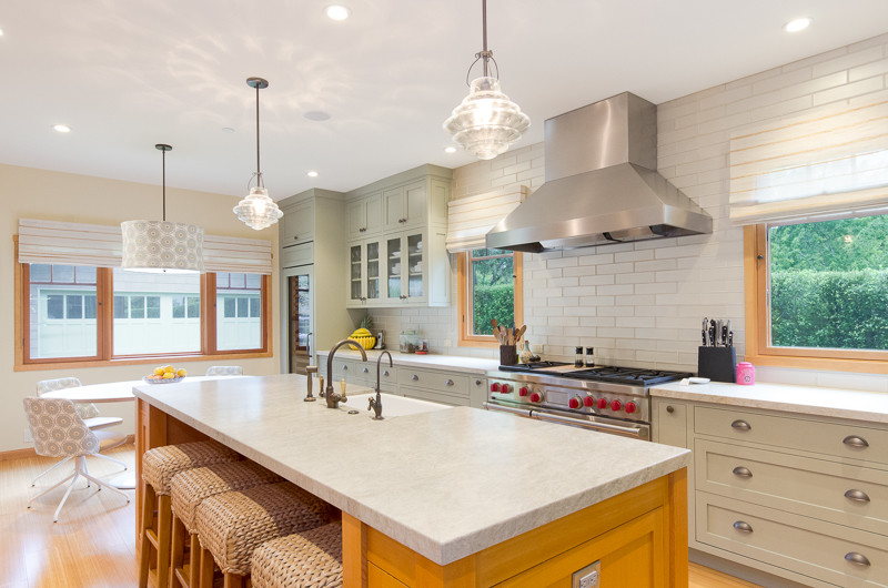 Photo of a beach style u-shaped kitchen in San Francisco with a submerged sink, shaker cabinets, green cabinets, granite worktops, beige splashback, metro tiled splashback, integrated appliances, light hardwood flooring and an island.