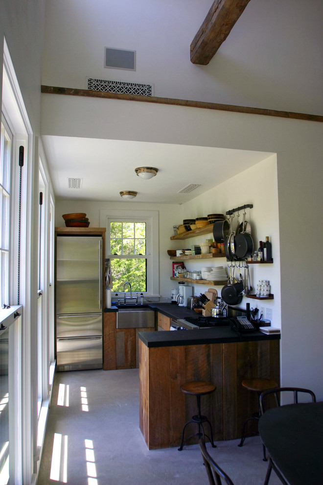 ニューヨークにある小さなカントリー風のおしゃれなキッチン (濃色木目調キャビネット、シルバーの調理設備、コンクリートの床) の写真