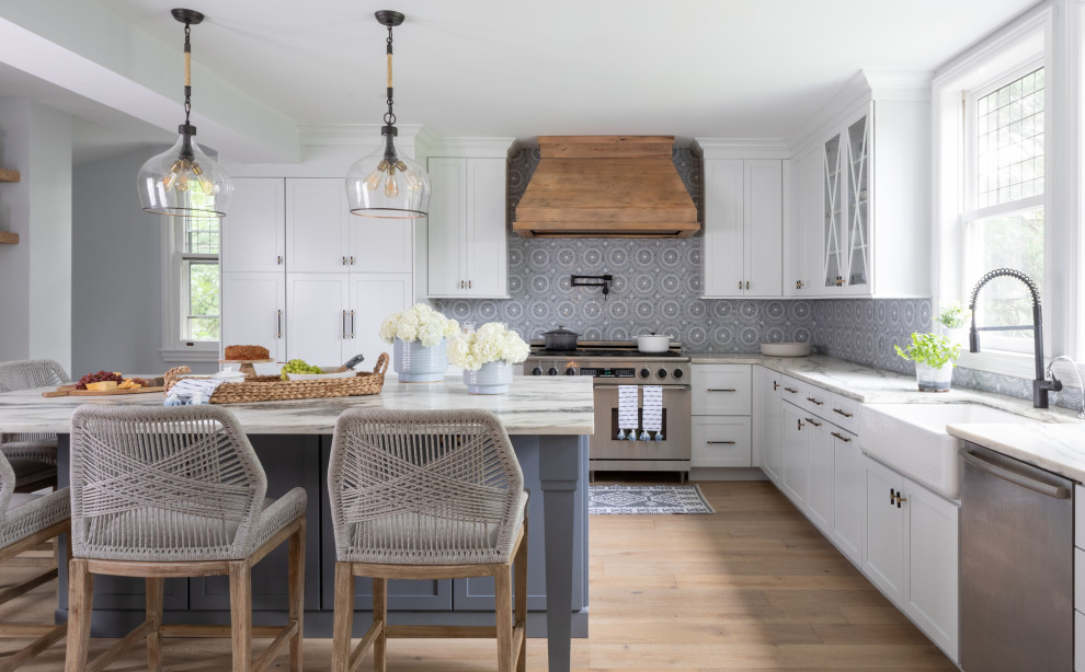 Bild på ett lantligt kök och matrum, med blått stänkskydd, rostfria vitvaror och en köksö