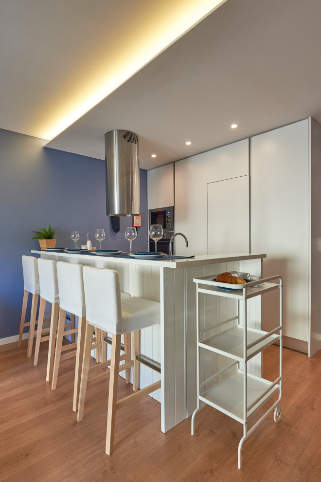This is an example of a small contemporary galley kitchen in Other with flat-panel cabinets, beige cabinets, integrated appliances, a breakfast bar, brown floors and beige worktops.