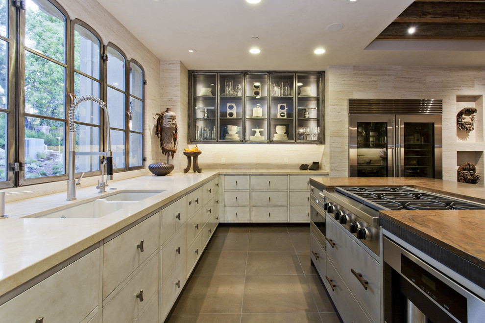 Example of a tuscan kitchen design in San Francisco with glass-front cabinets, stainless steel appliances and a double-bowl sink