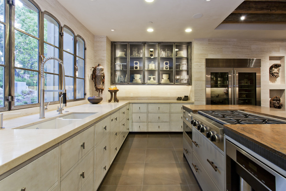 Bild på ett medelhavsstil kök, med luckor med glaspanel, rostfria vitvaror och en dubbel diskho