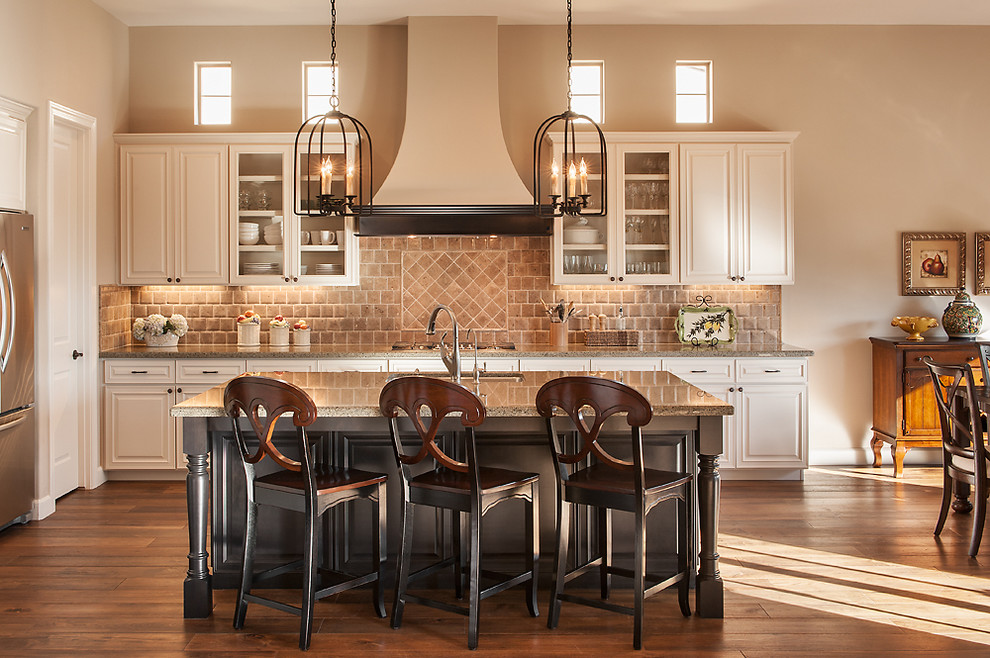 Open concept kitchen - traditional medium tone wood floor open concept kitchen idea in Phoenix with white cabinets, granite countertops, brown backsplash, stone tile backsplash, stainless steel appliances and an island