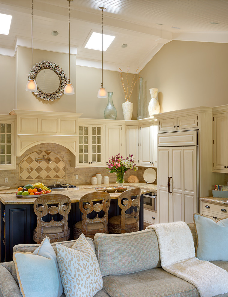 Inredning av ett klassiskt kök med öppen planlösning, med en rustik diskho, luckor med upphöjd panel, beige skåp, granitbänkskiva, beige stänkskydd, stänkskydd i stenkakel, rostfria vitvaror och en köksö