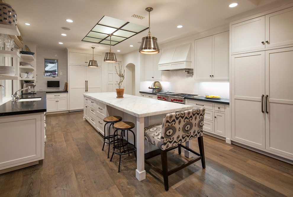 Design ideas for a large classic u-shaped kitchen/diner in Santa Barbara with a submerged sink, shaker cabinets, white cabinets, marble worktops, white splashback, ceramic splashback, stainless steel appliances, dark hardwood flooring and an island.