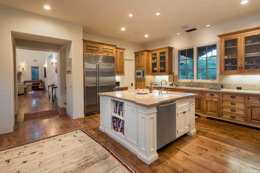 Example of a large tuscan u-shaped medium tone wood floor enclosed kitchen design in Santa Barbara with an undermount sink, beaded inset cabinets, medium tone wood cabinets, beige backsplash, mosaic tile backsplash, stainless steel appliances and an island