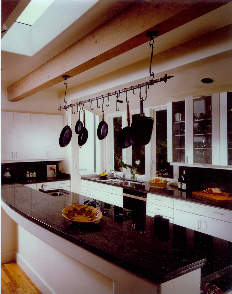 This is an example of a medium sized classic l-shaped open plan kitchen in Santa Barbara with glass-front cabinets, white cabinets, medium hardwood flooring, an island, a submerged sink, black splashback and black appliances.