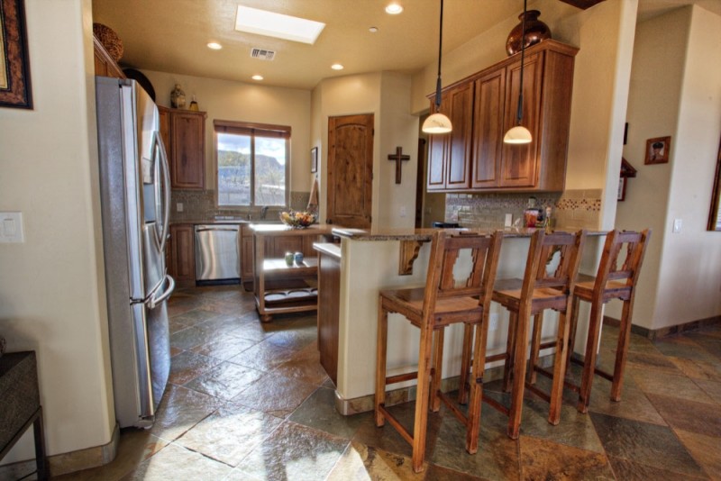 Foto på ett stort amerikanskt u-kök, med en undermonterad diskho, luckor med upphöjd panel, skåp i mellenmörkt trä, granitbänkskiva, beige stänkskydd, rostfria vitvaror och en halv köksö