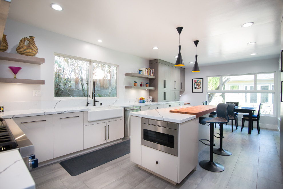 Inspiration for a large contemporary l-shaped porcelain tile and gray floor eat-in kitchen remodel in Los Angeles with a farmhouse sink, flat-panel cabinets, gray cabinets, quartz countertops, white backsplash, quartz backsplash, stainless steel appliances, an island and white countertops