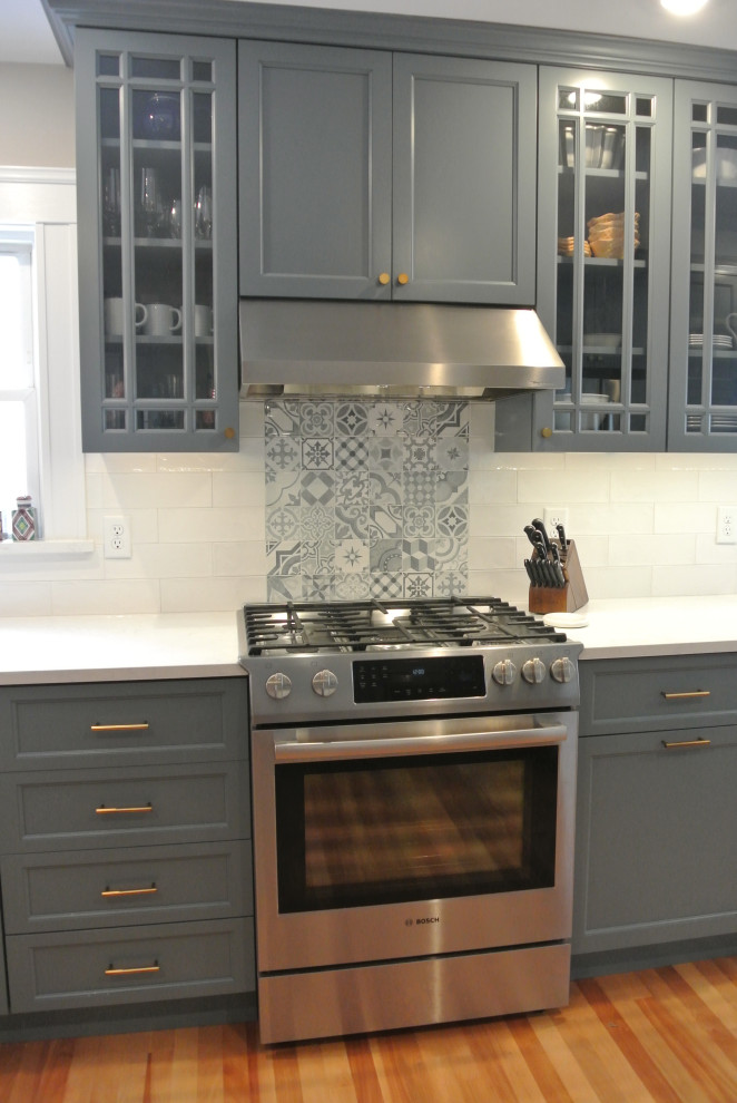 Klassisk inredning av ett mellanstort vit vitt kök, med en rustik diskho, skåp i shakerstil, blå skåp, bänkskiva i kvarts, grått stänkskydd, stänkskydd i keramik, rostfria vitvaror, korkgolv, en halv köksö och beiget golv