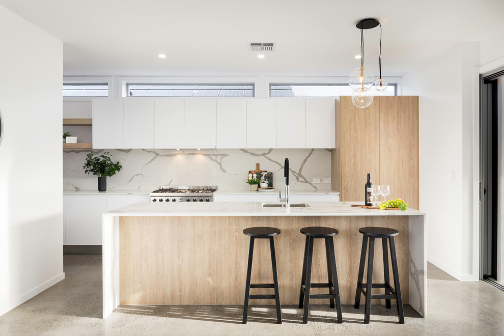 Inspiration for a scandinavian galley kitchen in Brisbane with a submerged sink, flat-panel cabinets, white cabinets, white splashback, stainless steel appliances, concrete flooring, an island, grey floors and white worktops.