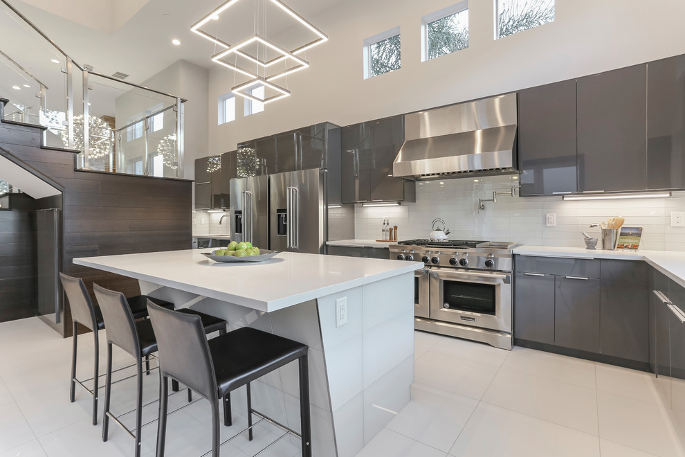 Design ideas for a large modern l-shaped enclosed kitchen in Sacramento with flat-panel cabinets, grey cabinets, composite countertops, white splashback, glass tiled splashback, stainless steel appliances, porcelain flooring, an island and white floors.