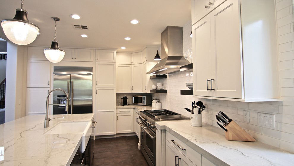 Lantlig inredning av ett avskilt, mellanstort vit vitt l-kök, med en rustik diskho, skåp i shakerstil, vita skåp, marmorbänkskiva, vitt stänkskydd, stänkskydd i tunnelbanekakel, rostfria vitvaror, betonggolv, en köksö och grått golv