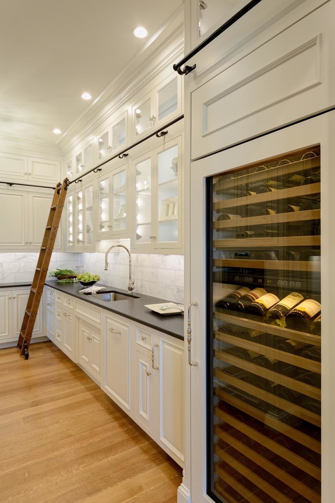 Example of a large classic l-shaped light wood floor kitchen design in Boston with an undermount sink, glass-front cabinets, white cabinets, white backsplash and paneled appliances