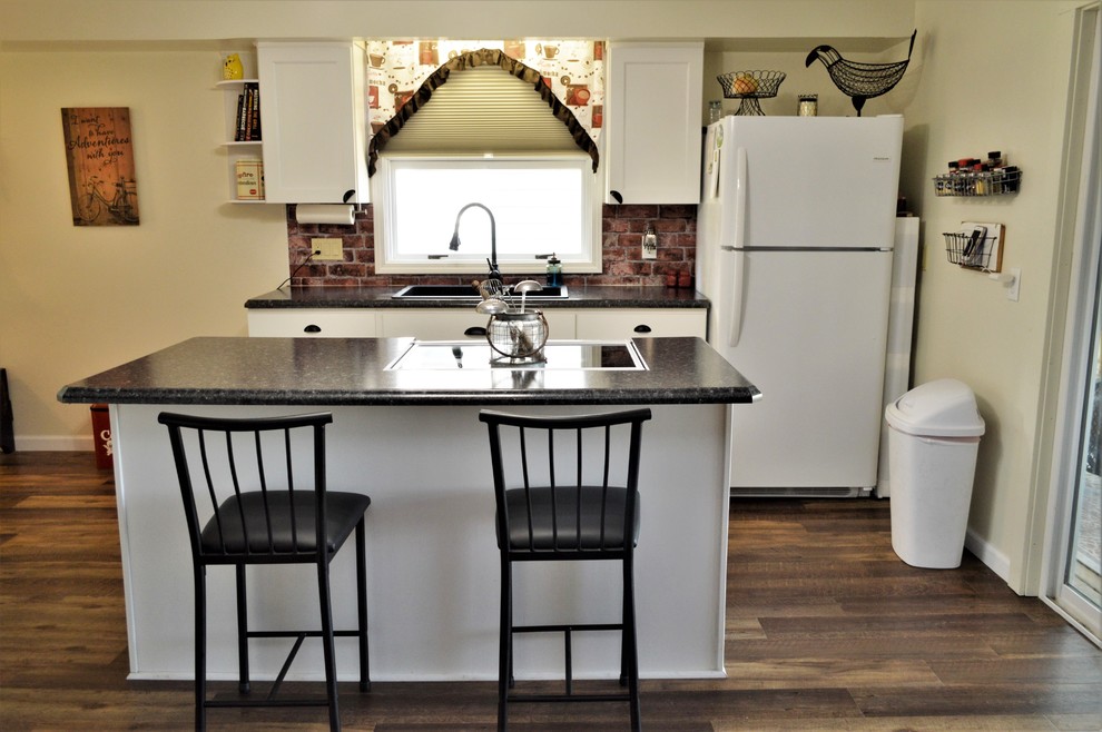 Immagine di una piccola cucina tradizionale con lavello da incasso, ante in stile shaker, ante bianche, top in laminato, paraspruzzi rosso, paraspruzzi in mattoni, pavimento marrone e top nero