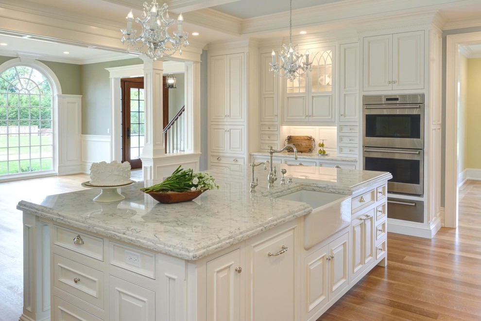 Large elegant l-shaped light wood floor and brown floor enclosed kitchen photo in Bridgeport with a farmhouse sink, beaded inset cabinets, white cabinets, marble countertops, gray backsplash, mosaic tile backsplash, paneled appliances and an island