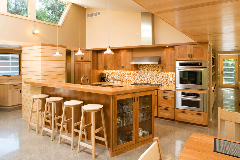 This is an example of a modern kitchen in Minneapolis with glass tiled splashback, stainless steel appliances, concrete flooring, a single-bowl sink, medium wood cabinets, recycled glass countertops, multi-coloured splashback and an island.