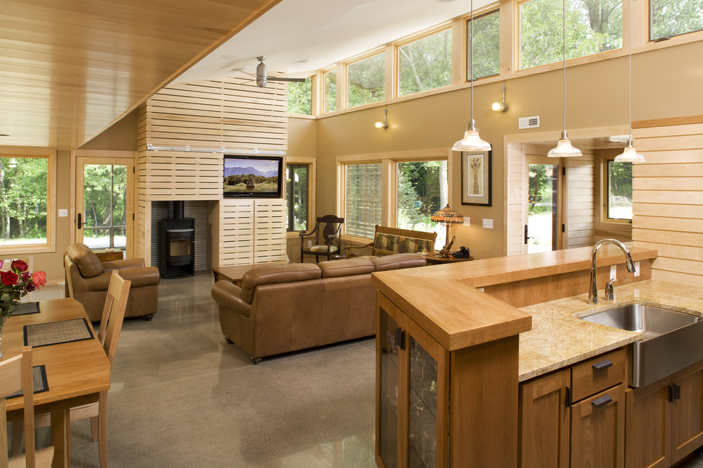 Bild på ett funkis kök, med en enkel diskho, skåp i mellenmörkt trä, bänkskiva i återvunnet glas, flerfärgad stänkskydd, stänkskydd i glaskakel, rostfria vitvaror, betonggolv och en köksö