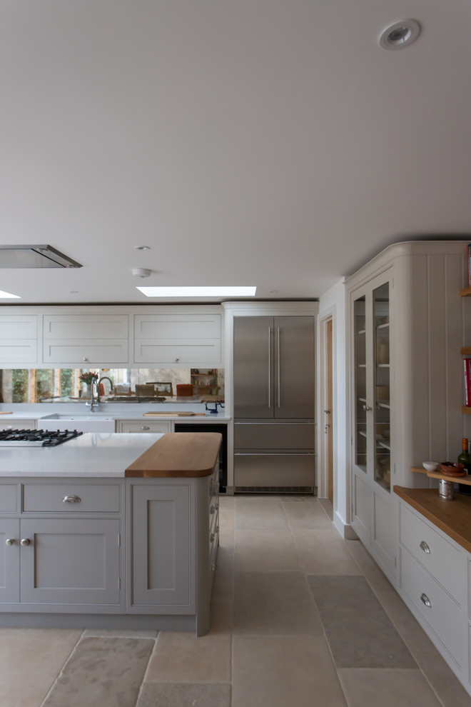 Foto di una grande cucina classica con ante in stile shaker, paraspruzzi a effetto metallico, paraspruzzi a specchio, pavimento in pietra calcarea e pavimento beige