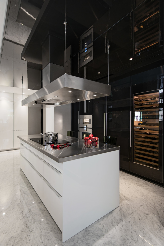 Immagine di una cucina minimal con lavello integrato, ante lisce, ante nere, top in acciaio inossidabile, paraspruzzi bianco, paraspruzzi in lastra di pietra e elettrodomestici in acciaio inossidabile