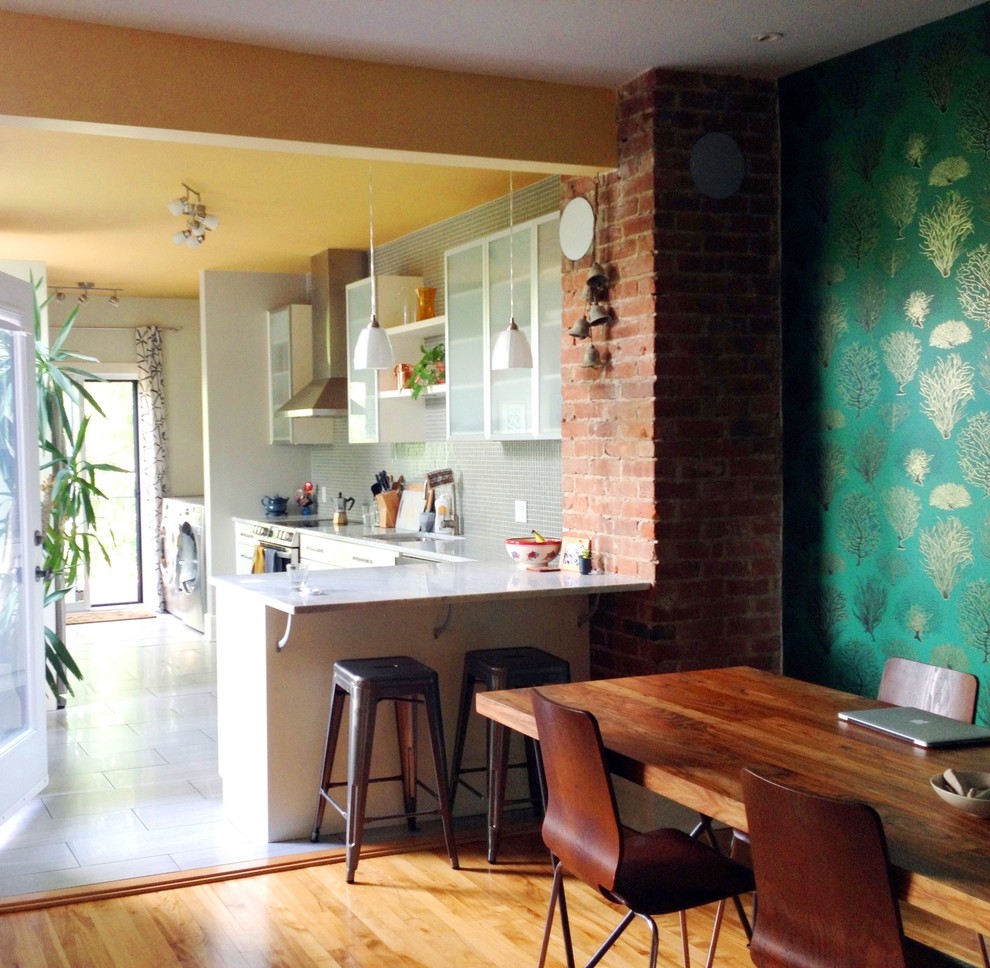 Cette photo montre une salle à manger ouverte sur la cuisine éclectique de taille moyenne avec un mur vert, un sol en bois brun, un sol marron et du papier peint.