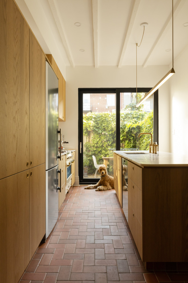 Exemple d'une cuisine parallèle tendance en bois brun avec plan de travail en marbre, îlot, un plan de travail blanc, un évier encastré, un placard à porte plane, un sol en brique et un sol rouge.