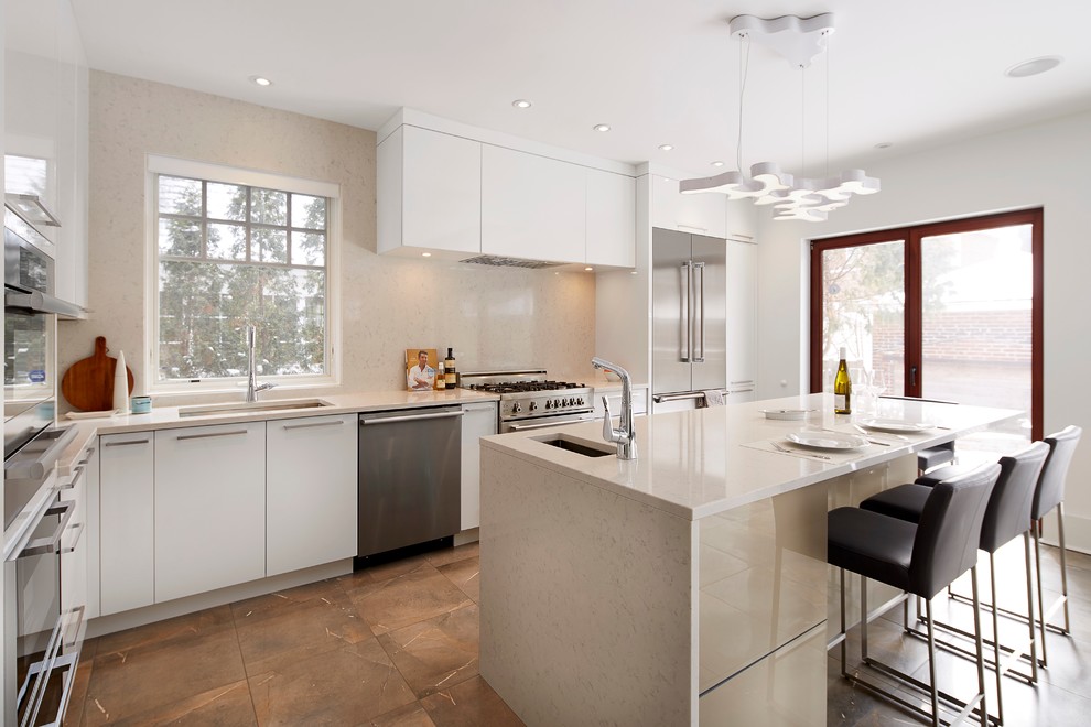 Mid-sized minimalist l-shaped ceramic tile eat-in kitchen photo in Montreal with an undermount sink, flat-panel cabinets, white cabinets, quartz countertops, beige backsplash, stone slab backsplash, stainless steel appliances and an island