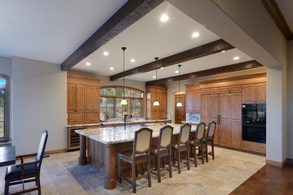 Inspiration for a large southwestern l-shaped travertine floor and beige floor open concept kitchen remodel in Other with an undermount sink, raised-panel cabinets, light wood cabinets, marble countertops, beige backsplash, stone slab backsplash, paneled appliances and an island