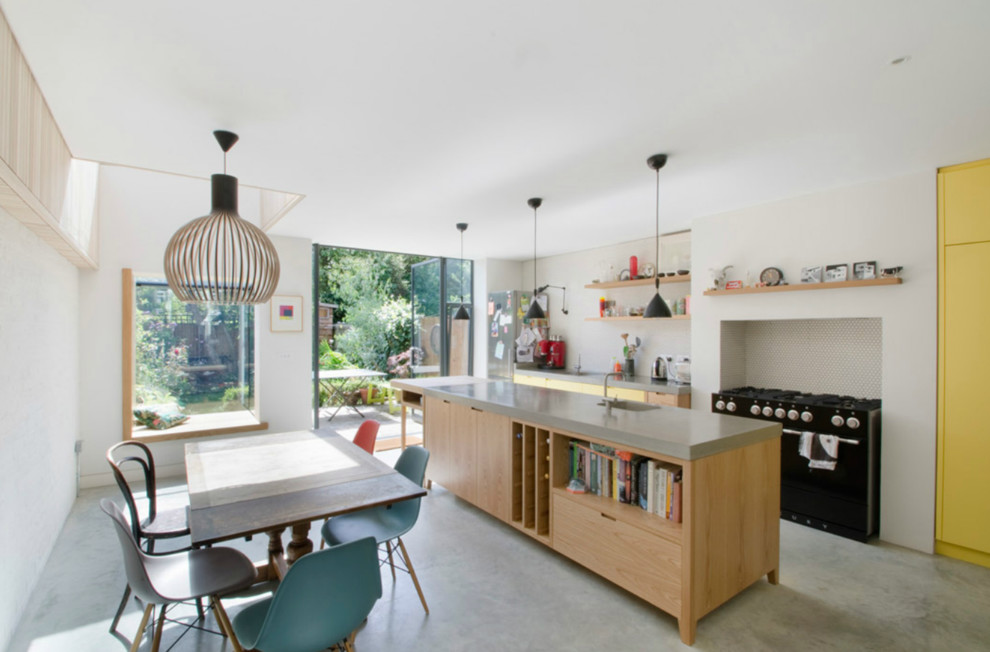 Photo of a medium sized contemporary single-wall kitchen/diner in London with flat-panel cabinets, light wood cabinets, concrete worktops, white splashback and an island.