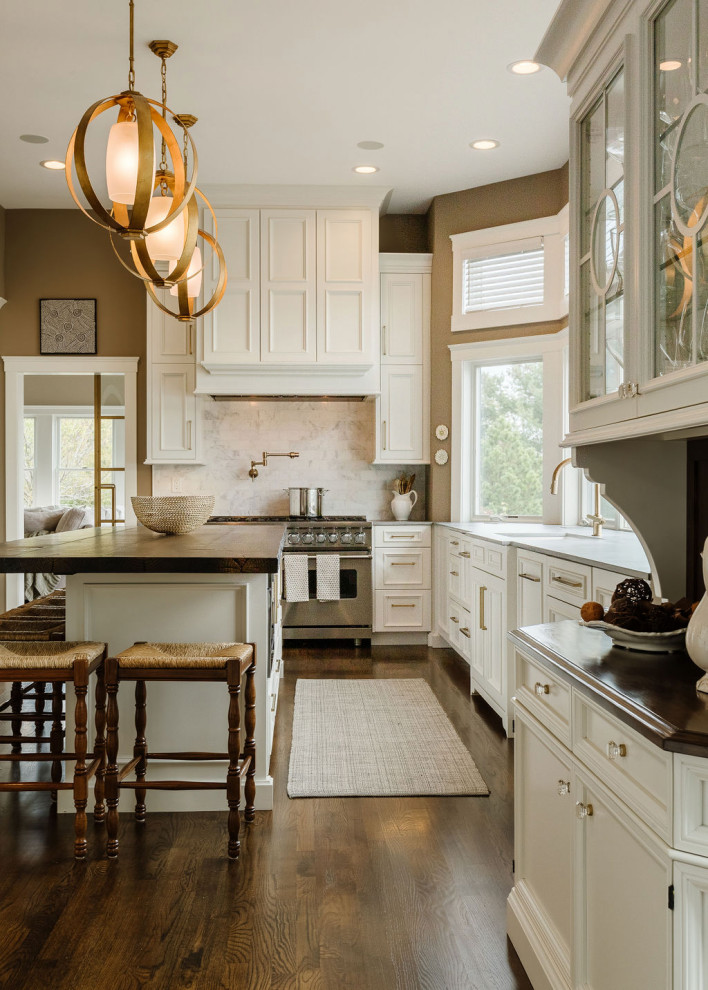 Inspiration för klassiska brunt u-kök, med vita skåp, rostfria vitvaror, mellanmörkt trägolv, en köksö, en undermonterad diskho, luckor med infälld panel, träbänkskiva, flerfärgad stänkskydd, stänkskydd i marmor och brunt golv