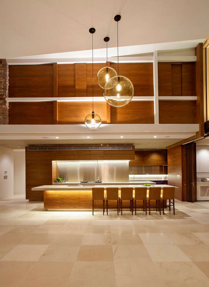 Idée de décoration pour une grande cuisine parallèle design en bois brun avec un placard à porte plane, une crédence en dalle métallique, un sol en travertin, îlot, une crédence métallisée et un sol beige.