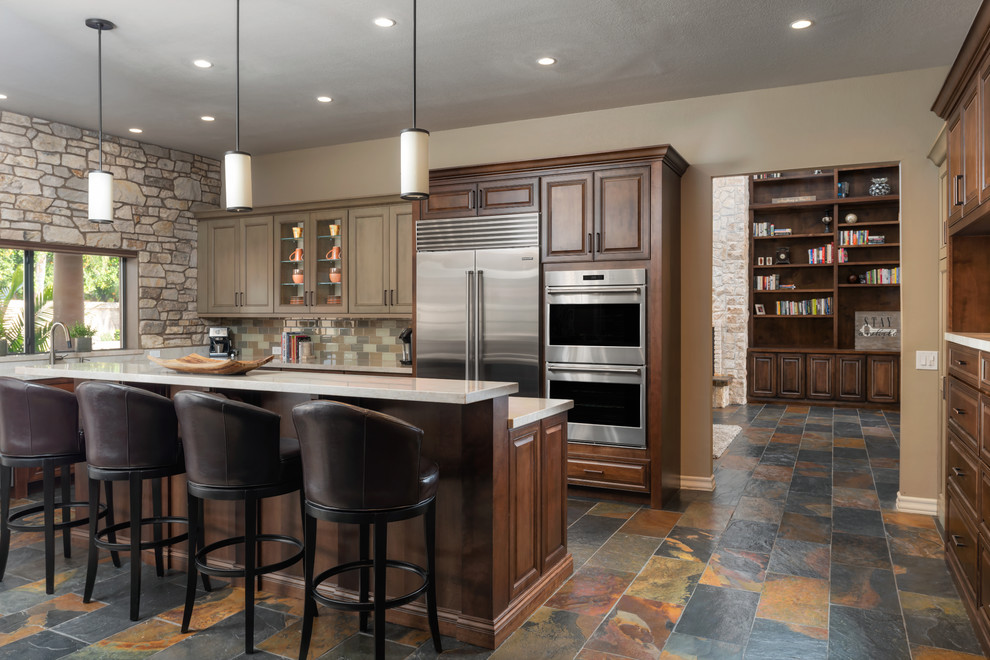 Elegant multicolored floor kitchen photo in Phoenix with raised-panel cabinets, dark wood cabinets, multicolored backsplash, subway tile backsplash, stainless steel appliances, an island and gray countertops