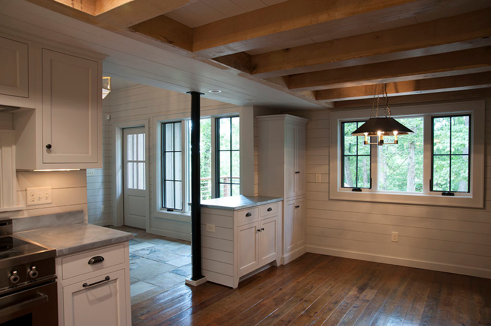 Foto på ett mellanstort rustikt kök, med luckor med infälld panel, vita skåp, bänkskiva i betong, vitt stänkskydd, stänkskydd i trä, rostfria vitvaror, mellanmörkt trägolv och brunt golv