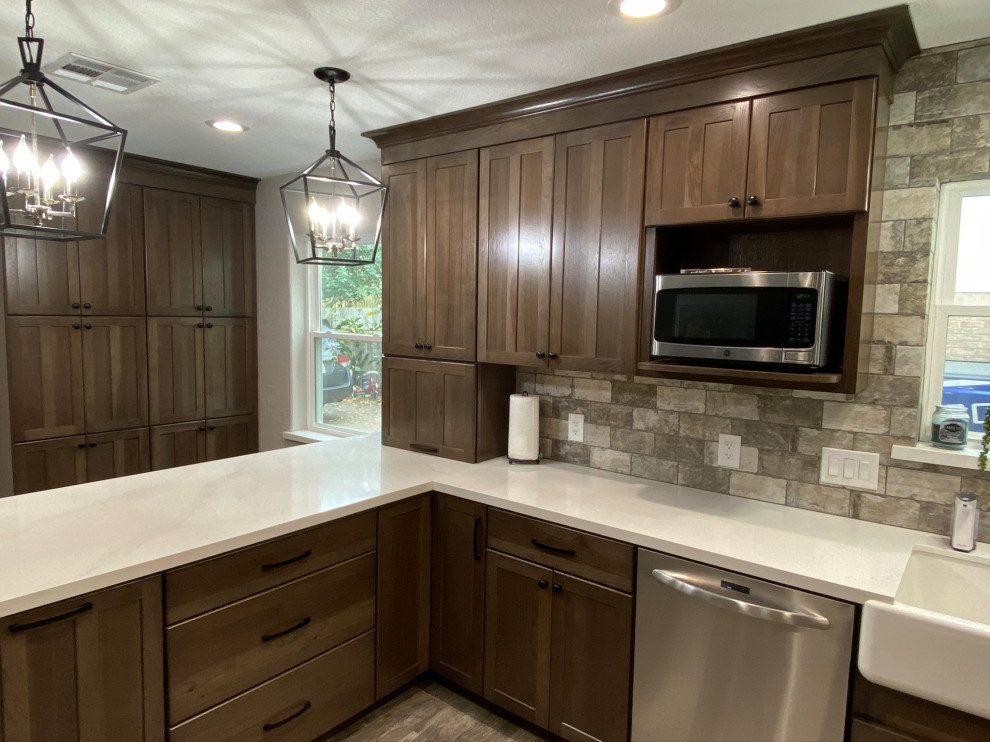 Foto på ett mellanstort amerikanskt vit kök, med en rustik diskho, skåp i shakerstil, bruna skåp, träbänkskiva, grått stänkskydd, stänkskydd i travertin, rostfria vitvaror, en halv köksö och grått golv