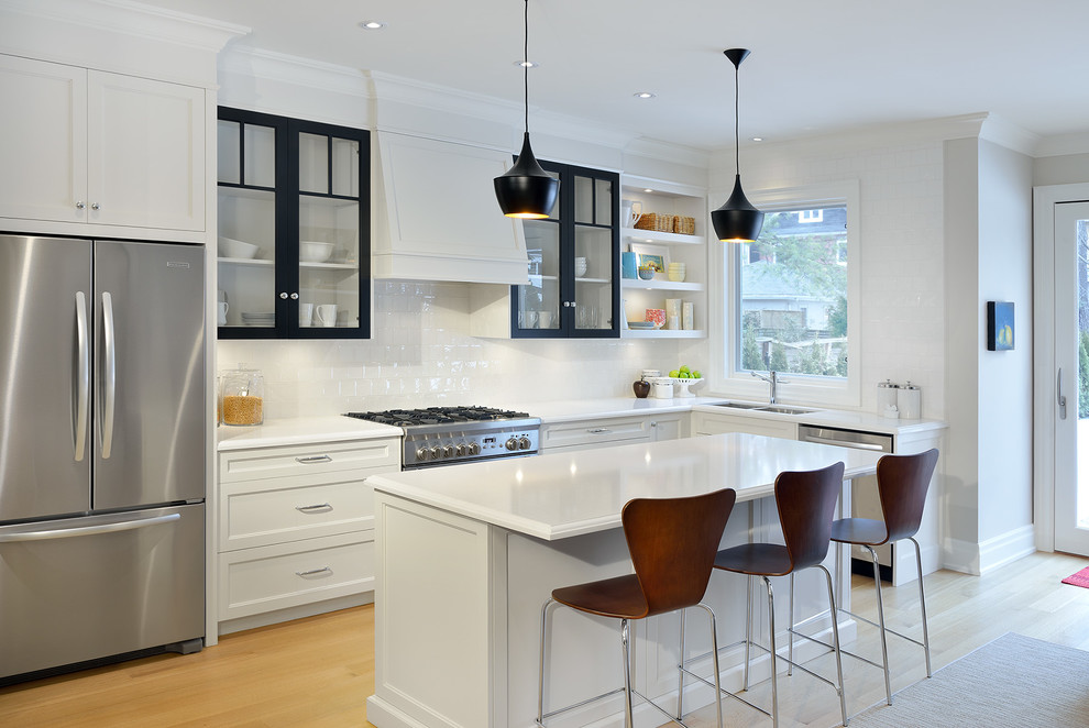Inspiration for a medium sized traditional l-shaped kitchen in Toronto with a submerged sink, recessed-panel cabinets, engineered stone countertops, white splashback, porcelain splashback, stainless steel appliances, light hardwood flooring and an island.
