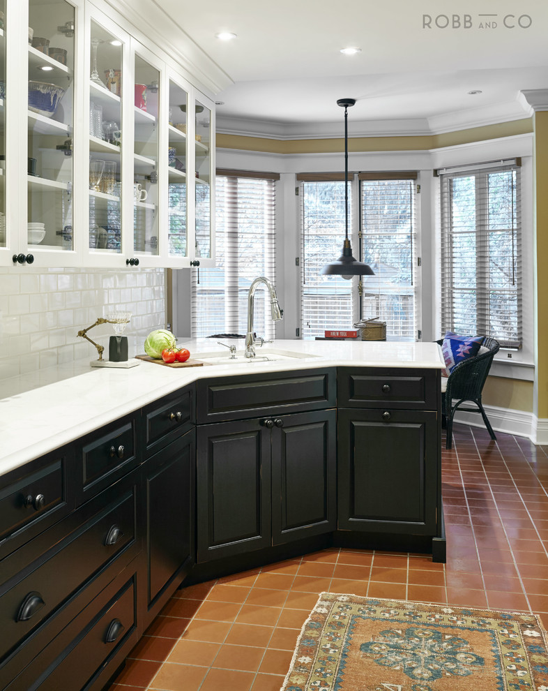 Klassisk inredning av ett mellanstort kök, med en dubbel diskho, luckor med upphöjd panel, vita skåp, bänkskiva i kvarts, vitt stänkskydd, stänkskydd i keramik, integrerade vitvaror, klinkergolv i terrakotta, en halv köksö och rött golv