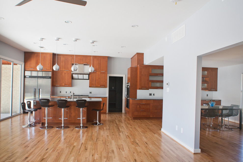 Modern inredning av ett stort linjärt kök och matrum, med en dubbel diskho, vitt stänkskydd, rostfria vitvaror, mellanmörkt trägolv, brunt golv, skåp i shakerstil, skåp i mellenmörkt trä, bänkskiva i zink och en köksö