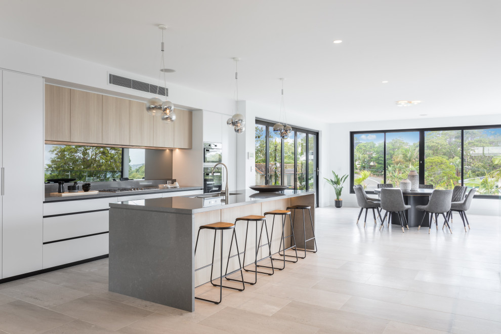 Zweizeilige Moderne Küche mit Unterbauwaschbecken, flächenbündigen Schrankfronten, weißen Schränken, hellem Holzboden, Kücheninsel, beigem Boden und grauer Arbeitsplatte in Sunshine Coast