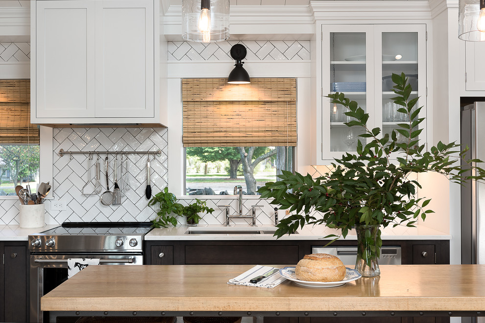 Example of a mid-sized farmhouse single-wall light wood floor and brown floor open concept kitchen design in Other with an undermount sink, beaded inset cabinets, white cabinets, quartz countertops, white backsplash, subway tile backsplash, stainless steel appliances and an island