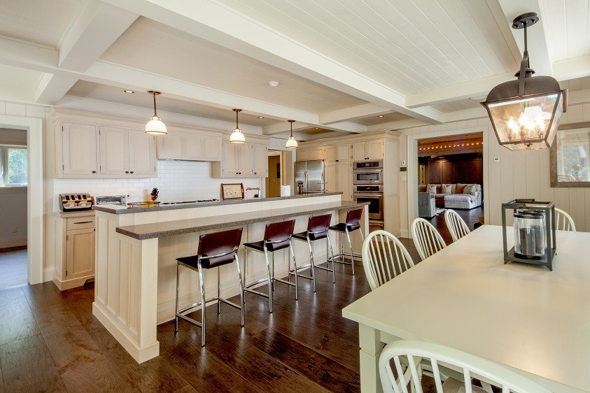 Bild på ett stort maritimt kök, med vitt stänkskydd, rostfria vitvaror, mörkt trägolv, en köksö och brunt golv