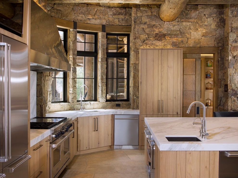 Inredning av ett rustikt mellanstort grå grått l-kök, med en undermonterad diskho, släta luckor, skåp i ljust trä, marmorbänkskiva, brunt stänkskydd, stänkskydd i stenkakel, rostfria vitvaror, en köksö och beiget golv