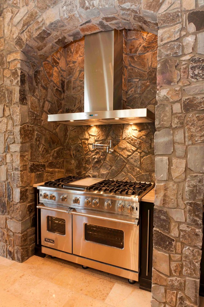 Exempel på ett klassiskt kök och matrum, med brunt stänkskydd, stänkskydd i sten, rostfria vitvaror och travertin golv