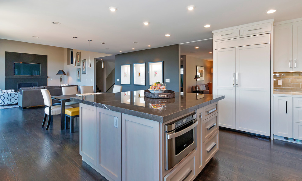 Example of a transitional dark wood floor eat-in kitchen design in San Francisco with an undermount sink, shaker cabinets, white cabinets, marble countertops, gray backsplash, glass tile backsplash, paneled appliances and an island