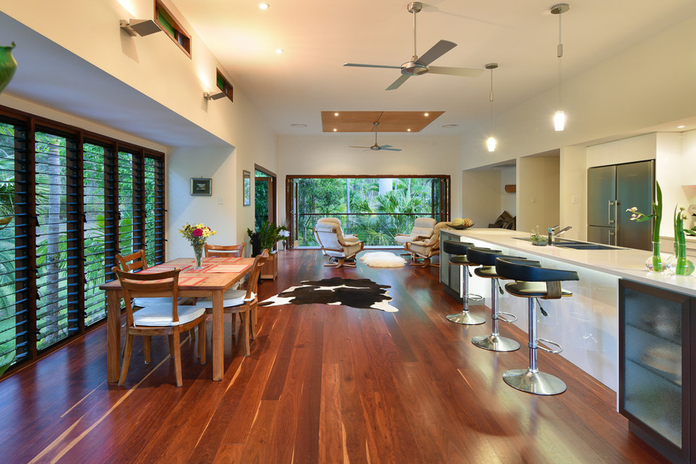 Immagine di una grande cucina tropicale con ante lisce, ante bianche, lavello a doppia vasca, paraspruzzi rosso, elettrodomestici in acciaio inossidabile, parquet scuro e pavimento marrone