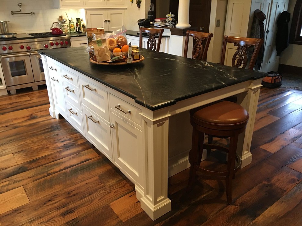 Exempel på ett mellanstort lantligt l-kök, med en rustik diskho, luckor med infälld panel, vita skåp, marmorbänkskiva, vitt stänkskydd, stänkskydd i tunnelbanekakel, rostfria vitvaror, mellanmörkt trägolv och en köksö