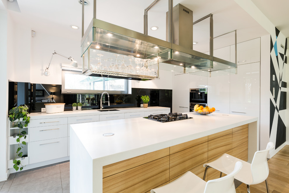 Bild på ett stort skandinaviskt linjärt kök och matrum, med en undermonterad diskho, släta luckor, vita skåp, svart stänkskydd, rostfria vitvaror, mellanmörkt trägolv, en köksö och brunt golv