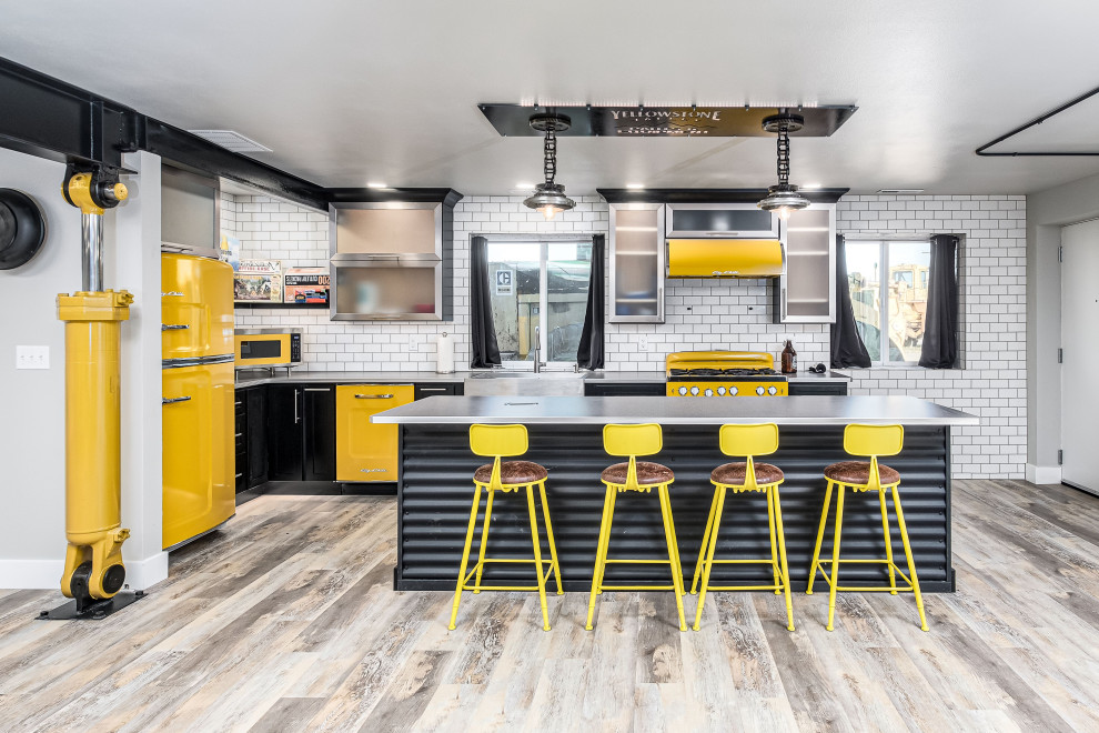 Example of a large urban laminate floor and beige floor eat-in kitchen design in Other with glass-front cabinets, black cabinets, stainless steel countertops, white backsplash, subway tile backsplash, colored appliances and an island